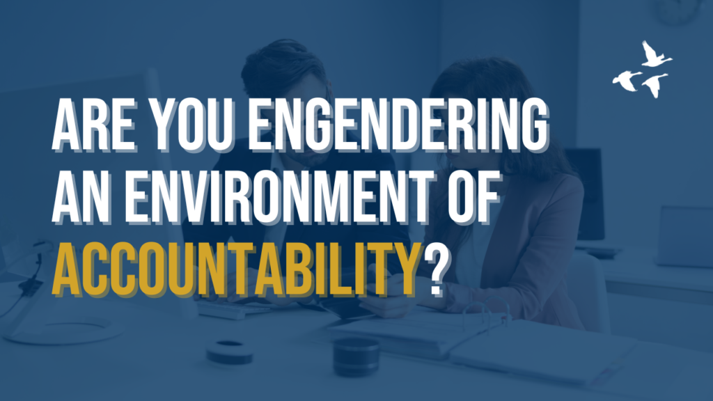 A man and woman working together in an office setting, deeply engaged in conversation, with the overlay text: "Are you engendering an environment of accountability?" The image and text together highlight the importance of fostering a culture where responsibility and trust are integral to team dynamics